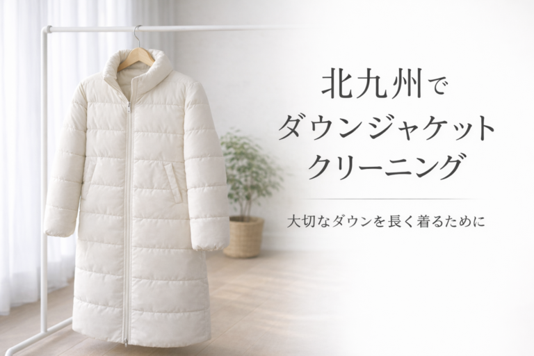 Long white down jacket hanging on a wooden hanger in a bright minimalist room with text about down jacket cleaning services in Kitakyushu.