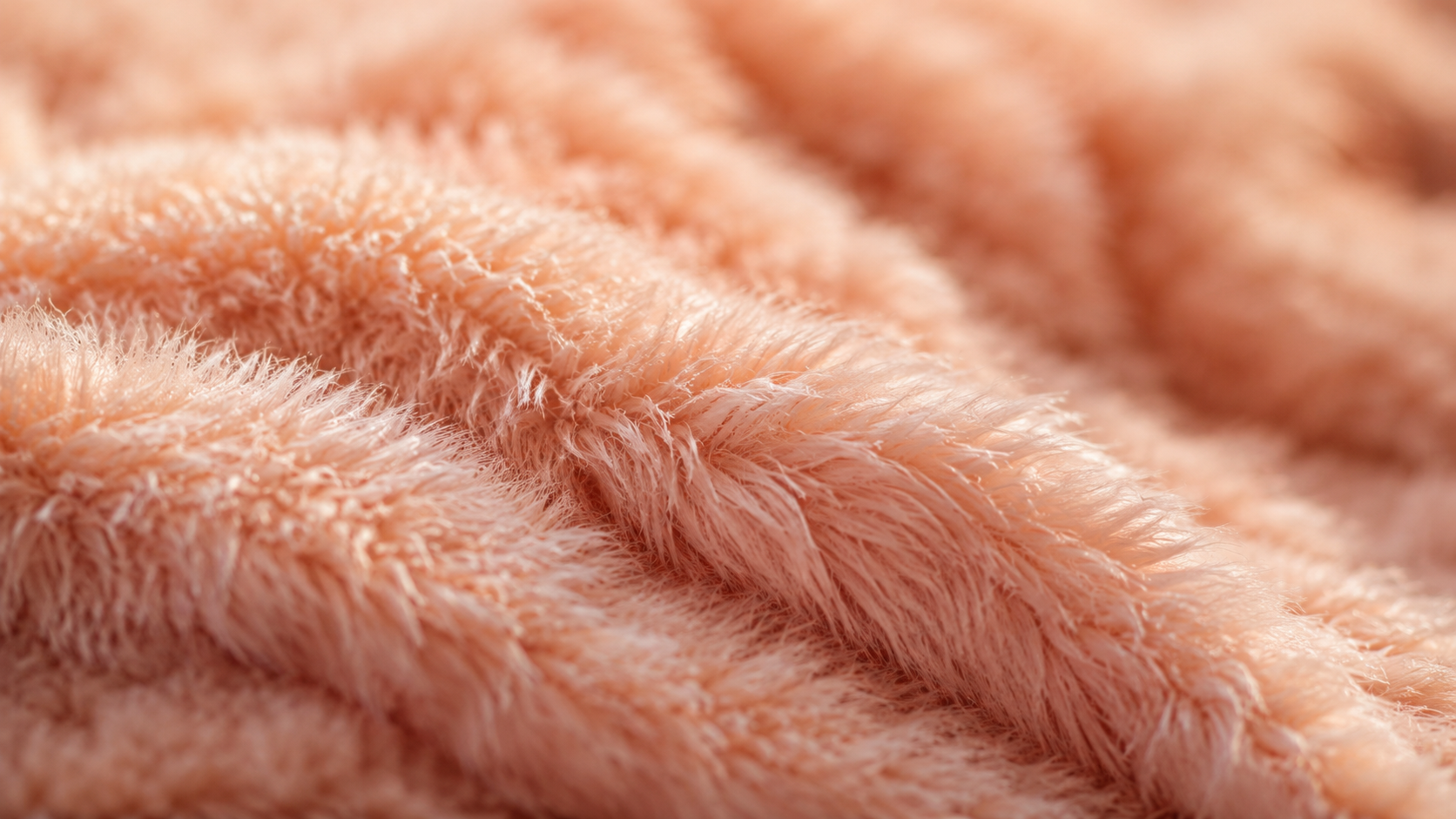 パステルピーチピンクのジェラートピケ風モコモコ素材(プラッシュベアファー)のマクロクローズアップ。繊細な起毛繊維が立ち上がる様子が見える。ポリエステル・ナイロンの起毛加工の特徴を示す素材詳細。北九州市小倉南区のファミリークリーニングが解説。