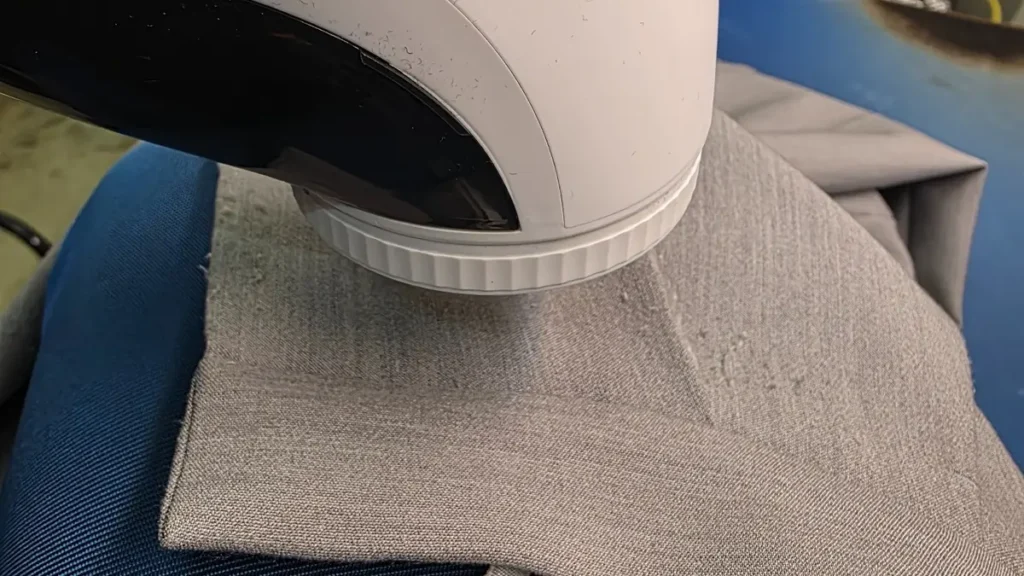 グレーの衣類を平らに置き、IWASHN毛玉取り器JL-WT01を軽く当てている作業風景